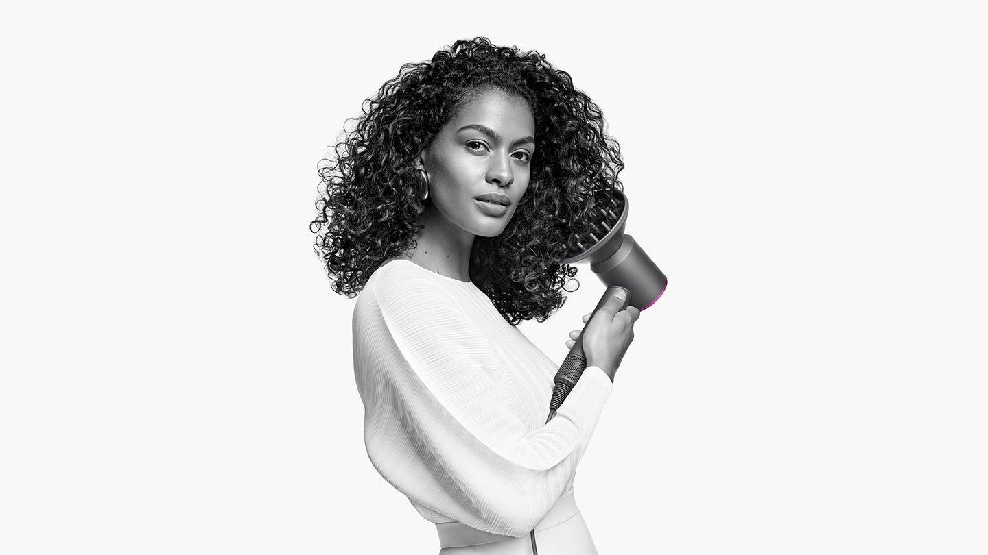 Woman holding Dyson Supersonic hair dryer with diffuser attachment